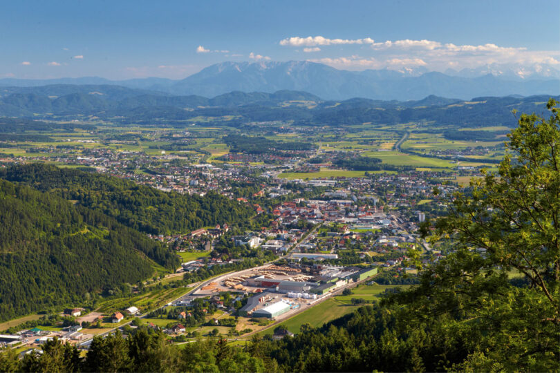 Häuser und Straßen eingebettet in hügelige, bewaldete Landschaft.