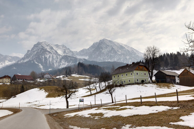 Verschneite Szenerie mit Häusern, dahinter ein Berg.