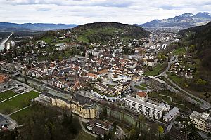 Luftaufnahme einer Kleinstadt mit Fluss, Altstadt, Hügeln im Hintergrund und teils bewölktem Himmel.