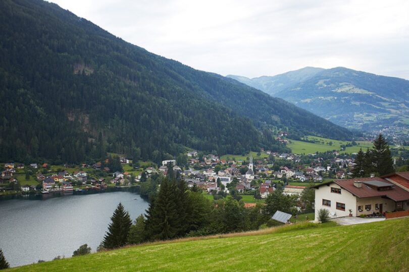 Ruhiger See am Ortsrand, umgeben von Bergen.