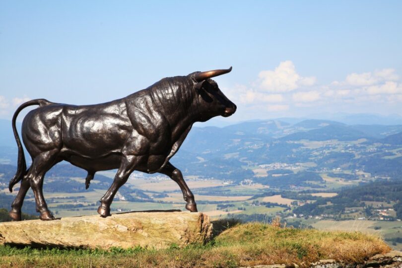 Große Stierstatue vor sanften Hügeln.