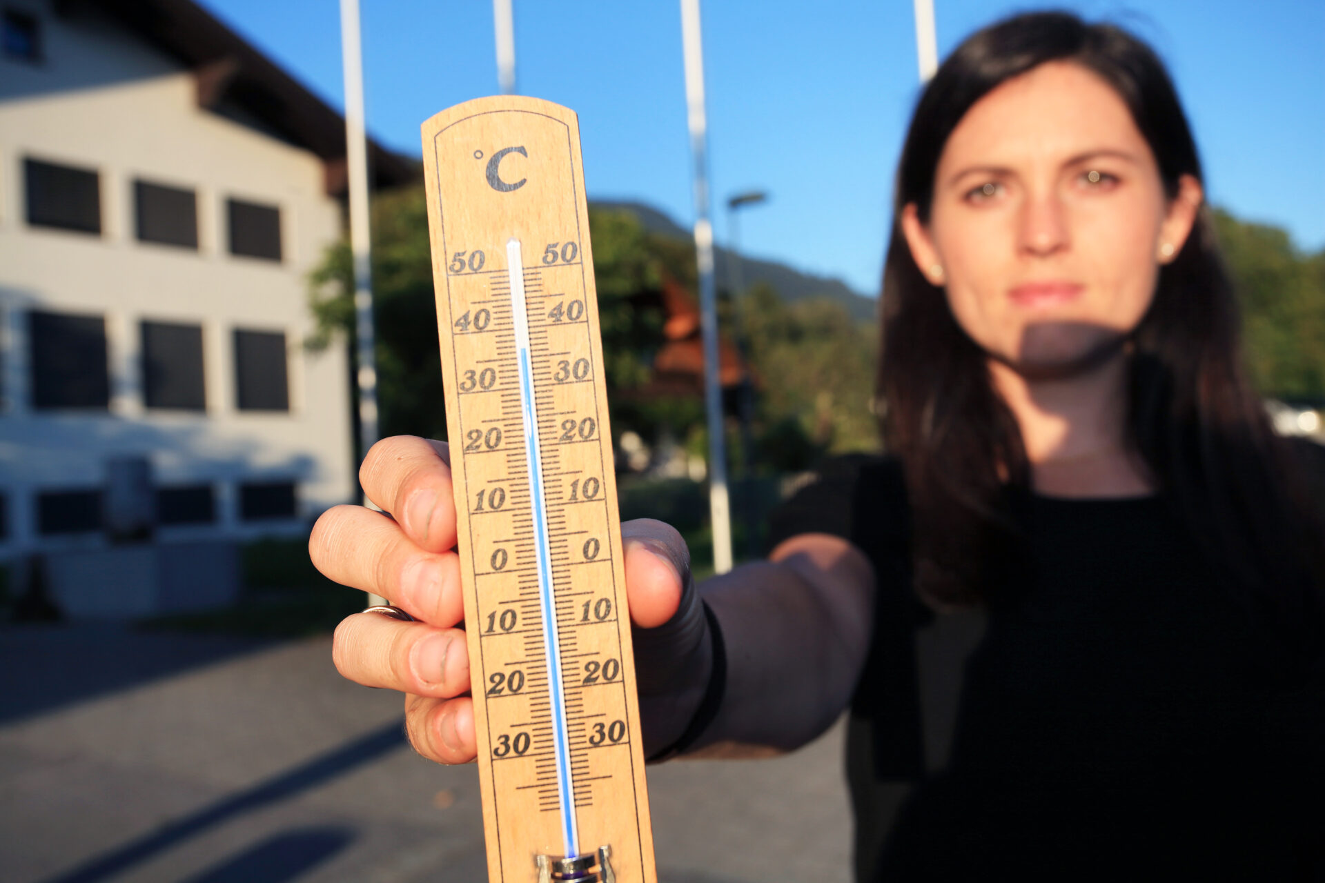 Holzthermometer mit Celsius-Skala, zeigt Temperaturen von über 30 Grad an, gehalten von einer Person.