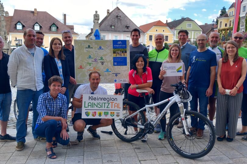 Gruppe von Personen steht vor einer Karte des Alltagsradwegenetzes. Eine Person hält ein Schild mit 'Kleinregion Lainsitztal'. Im Vordergrund steht ein Mountainbike.