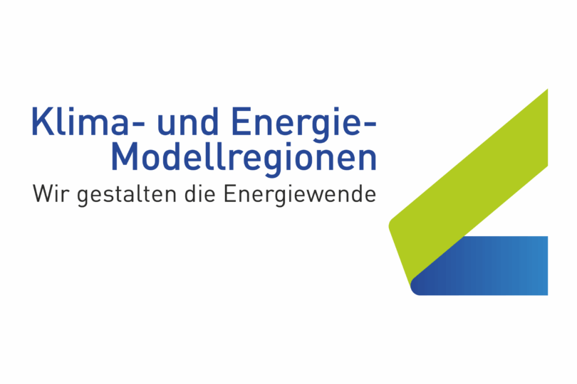 Logo von KEM (Klima- und Energie-Modellregionen) mit dem Slogan 'Wir gestalten die Energiewende'. Enthält grüne und blaue geometrische Formen.