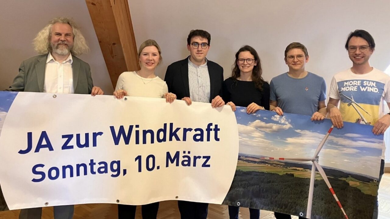 Menschen vor Plakat zur Windkraft