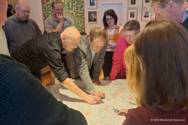 Menschen stehen um einen Tisch mit einer Karte herum und zeichnen etwas ein.