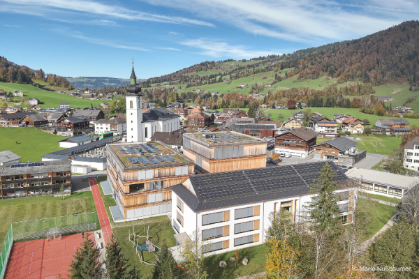 Dorf mit mehrstöckigen Gebäuden und Kirche in Natur mit Wald.