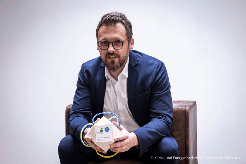 Mann, der mit Trophäe auf einem Ledersessel sitzt.