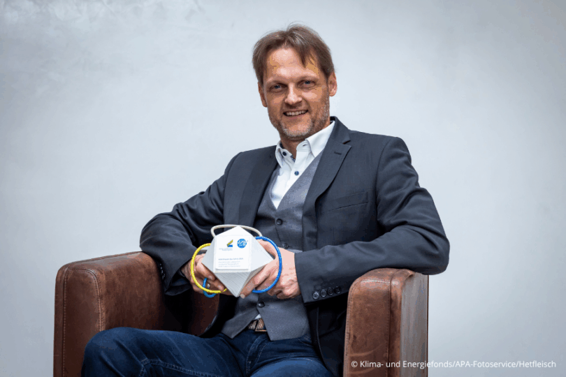 Mann, der mit Trophäe auf einem Ledersessel sitzt.