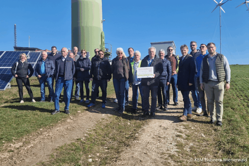 Menschen stehen vor einem Windrad.