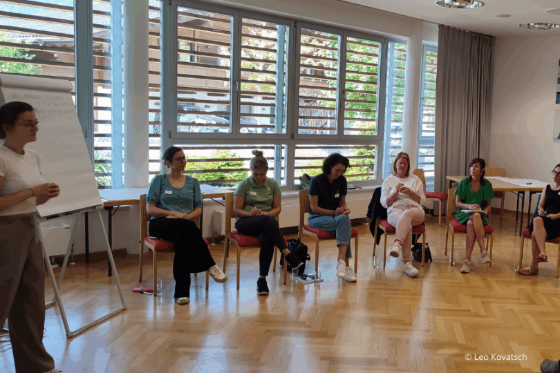 Schulungsraum mit Vortragender mit Flip Chart und sitzenden Teilnehmerinnen.