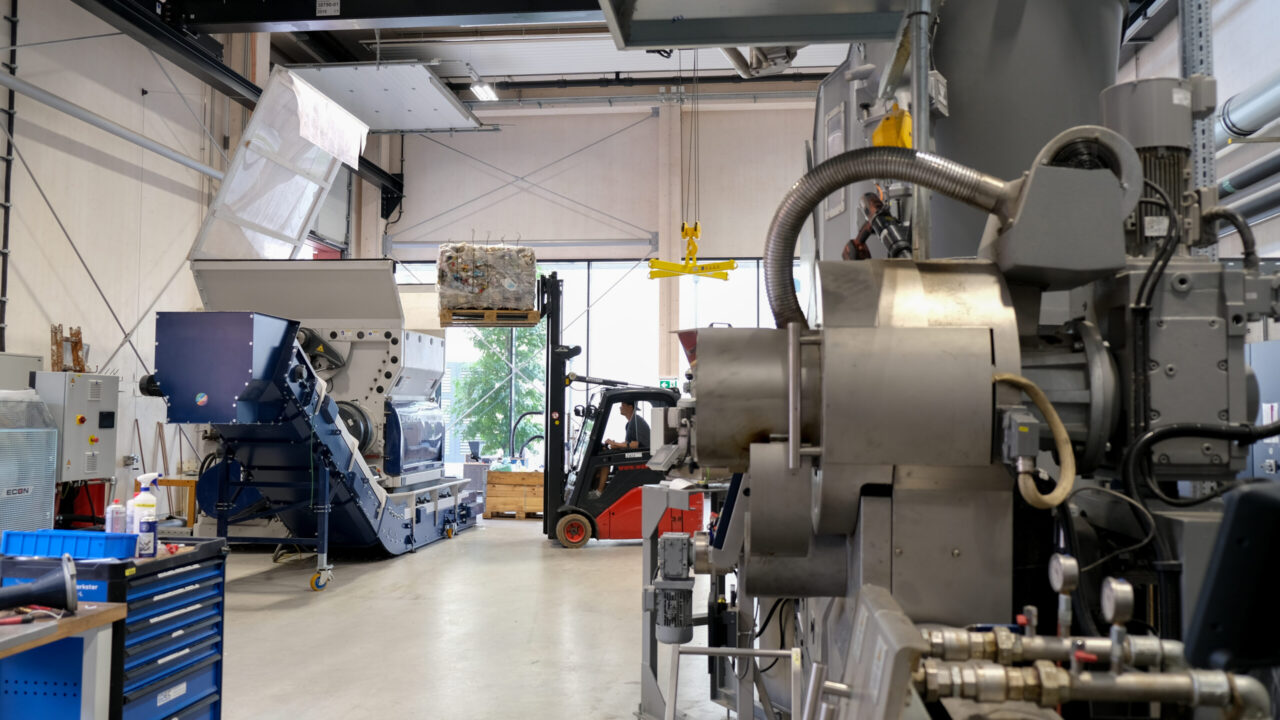 Foto eines Gabelstaplers in einer Fertigungshalle, der einen Ballen in eine Maschine lädt