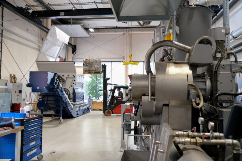 Foto eines Gabelstaplers in einer Fertigungshalle, der einen Ballen in eine Maschine lädt