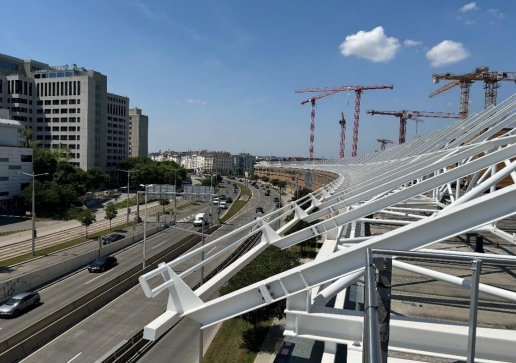 Moderne Stadtlandschaft mit geschwungenen weißen Strukturen, Gebäuden, Straßen und Baukränen.