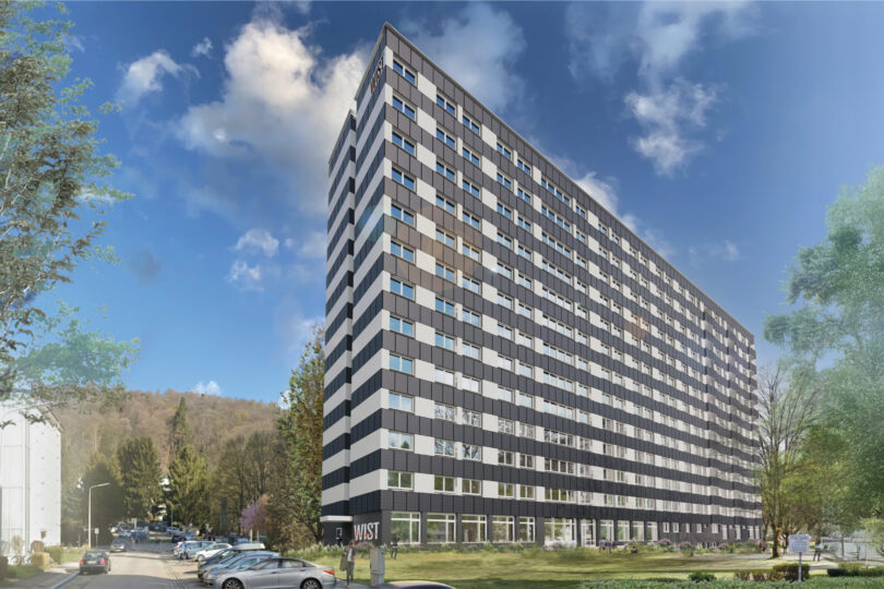 Modernes Hochhaus mit Solaranlagen unter einem blauen Himmel mit Wolken.