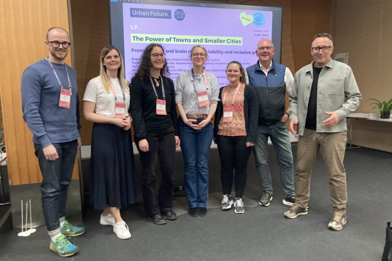 Resner:innen der Session stehen vor Leinwand für ein Gruppenfoto